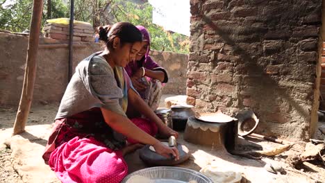 Domestic-life-of-young-Indian-girls-preparing-traditional-chapati-bread-with-rolling-pin,-Rajasthan