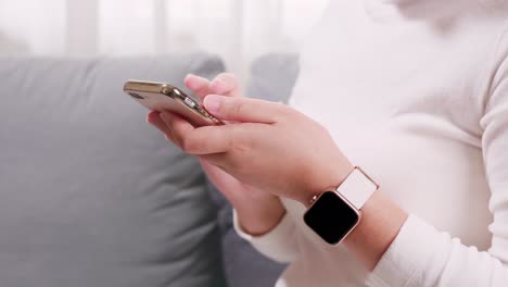 Nahaufnahme-Einer-Handfrau,-Die-Smartphone-Und-Smartwatch-Im-Wohnzimmer-Für-Geschäfts--Und-Einkaufsinternet--Und-Sms-kommunikation-Verwendet