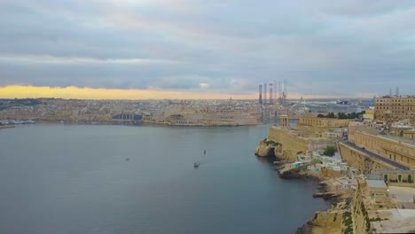Un-Dron-Volando-Sobre-El-Gran-Puerto-Desde-Tat-St-Elmo-Hacia-El-Monumento-De-La-Campana-En-Los-Jardines-Barrakka-En-Valletta-Malta