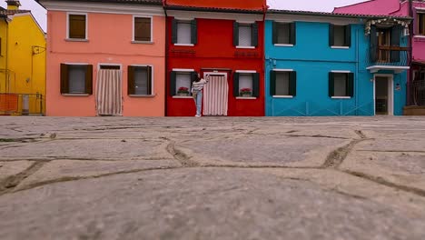 Low-angle-ground-surface-first-person-pov-of-colorful-houses-of-Burano-village-and-woman-standing