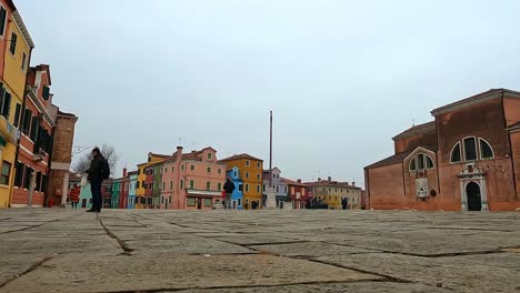 Low-angle-ground-surface-first-person-pov-of-Burano-main-square-with-tourists-and-San-Martino-church