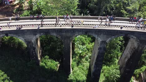 Pull-Back-Shot-Of-Tourists-Laying-Down-On-Nine-Arches-Railway-Bridge,-Demodara,-Sri-Lanka