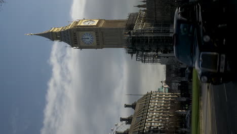 Ein-Vertikales-Video-Von-Einem-Belebten-Bürgersteig,-Während-Fahrzeuge-über-Den-Parliament-Square-In-London-Fahren,-In-Der-Ferne-Der-Wunderschön-Restaurierte,-Ikonische-Big-Ben-Glockenturm,-Beleuchtet-Von-Der-Morgensonne,-England