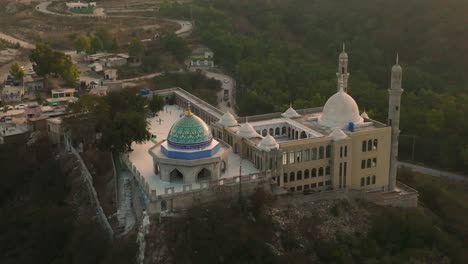 Aerial-View-Flying-Towards-Masjid-e-Aulia-Kallar-kahar-With-Amazing-Green-Dome-At-Chakwal,-Pakistan