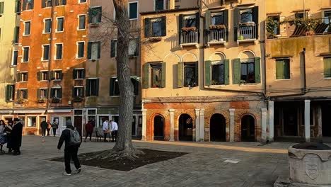 People-walk-in-main-square-of-Venetian-Ghetto-or-Campo-del-Ghetto-Nuovo-at-Jewish-quarter-of-Cannaregio-in-Venice,-Italy
