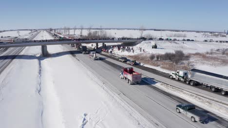Aerial-of-trucks-passing-under-overpass-as-supports-cheer