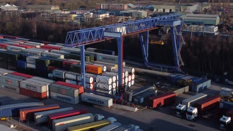 Shipping-container-crane-lift-unloading-heavy-cargo-export-crate-containers-in-shipyard-aerial-view