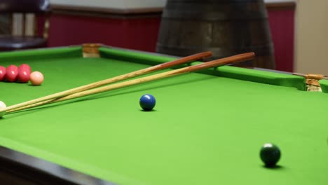 Green-pool-table-with-balls-and-cue