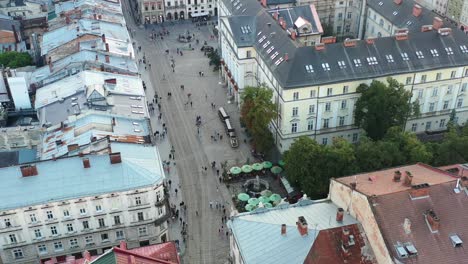 Turistas-Caminando-Por-Las-Calles-De-La-Plaza-Rynok-En-Lviv-Ucrania-Durante-La-Puesta-De-Sol,-Rodeados-Por-El-Ayuntamiento-Y-Edificios-Europeos