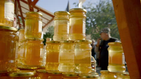 FAST-PAN-to-stacked-jars-of-honey-at-the-market-backlit-by-the-sun