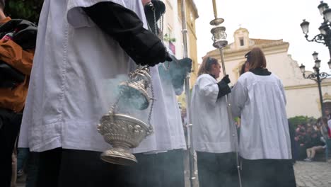An-altar-girl-swings-a-censer-burning-incense-to-clear-the-way-during-a-Holy-Week-procession-in-Cadiz,-Spain