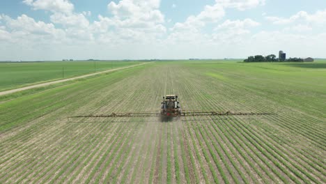 Aerial,-tractor-spraying-pesticides-on-crops-in-rural-agricultural-farm-field