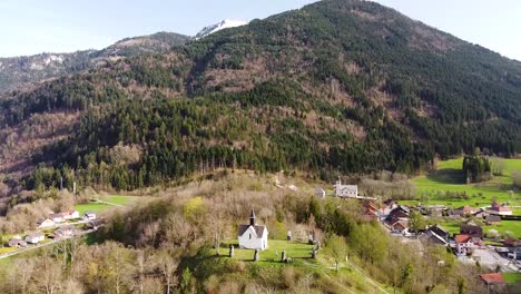 Drone-Shot-of-a-Chapel-on-top-of-a-Hill-in-front-of-Alpine-Mountains