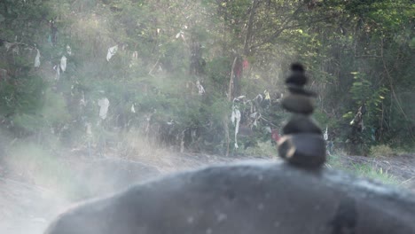 Balanced-stones-with-steam-emanating-from-the-thermal-hot-springs-of-Rio-Caliente-El-Salvador,-Wide-rack-focus-shot