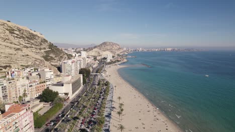 Aerial-backwards-view-over-a-beautiful-beach-in-Alicante,-Spain