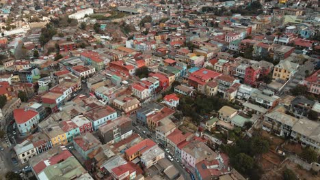 Aerial-lowering-over-charming-colorful-houses-revealing-Valparaiso-hillside-city-in-background-from-Cerro-Alegre,-Chile