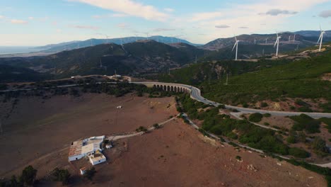 Flying-through-wind-farms-in-Tarifa,-Spain-at-sunset-with-mountains-in-the-background