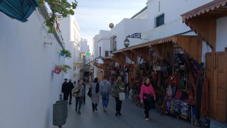 locals-and-tourists-stroll-in-bustling-colorful-souk-of-Tangier-Medina,-Morocco