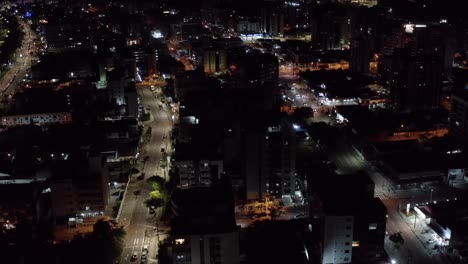 Tilt-up-aerial-drone-night-shot-of-the-tropical-beach-capital-city-of-Joao-Pessoa,-Paraiba,-Brazil-from-the-Tambaú-neighborhood-with-skyscrapers,-apartments,-and-a-small-streets-with-low-traffic