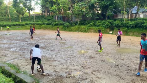 Enthusiastic-Asian-men-play-an-intense-game-of-mini-football-or-soccer-on-a-muddy-local-field