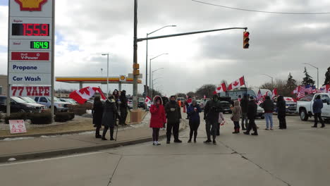 Demonstranten-Halten-Amerikanische-Und-Kanadische-Flaggen-In-Der-Nähe-Einer-Tankstelle-Und-Setzen-Sich-Für-Demokratie-Und-Politischen-Aktivismus-Ein