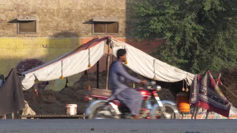 -Makeshift-Roadside-Camp-Made-By-Local-Due-To-Flooding-In-Sindh,-Pakistan-With-Traffic-Going-Past