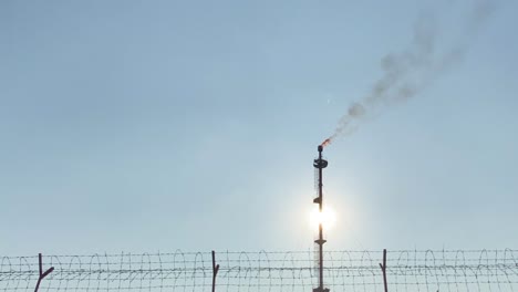 Establisher-view-of-Gas-Flare-smokestack-industry,-clear-blue-sky,-pan