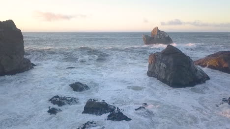 Aerial-Drone-of-waves-crashing-against-rocks-and-birds-flying-over-water-at-Sue-Meg-State-Park