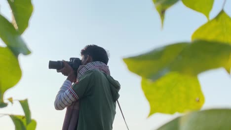 Portrait-of-South-Asian-young-man-taking-photos-of-nature,-leaf-in-front-of-lens