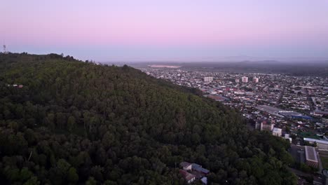 Fly-over-Cerro-Ñielol-and-the-city-of-Temuco-with-a-purple-sunset-and-the-Llaima-volcano-in-the-background