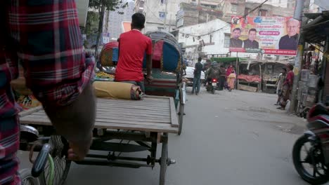 Blick-Aus-Der-Ersten-Person-Von-Einem-Rikscha-Beifahrersitz-Aus,-Während-Ein-Rikscha-Fahrer-Durch-Die-Straßen-Von-Dhaka-Fährt