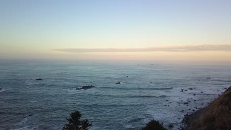 Aerial-drone-of-Pacific-Northwest-coast-and-ocean-at-dawn-with-evergreens-and-rocks