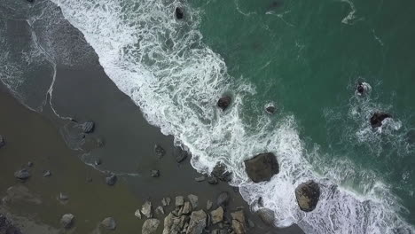 Aerial-drone-view-looking-down-on-Pacific-Northwest-beach-and-waves-with-rocks