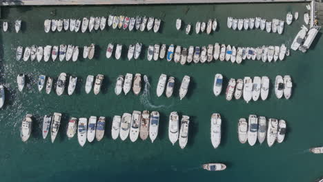 Top-down-aerial-footage-of-a-group-of-boats-that-are-anchored-off-of-Sorrento,-Italy-with-boats-traveling-through-them