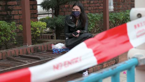 A-woman-wearing-a-face-mask-sits-next-to-a-closed-public-playground-due-to-the-Covid-19-Coronavirus-outbreak-and-restrictions-in-Hong-Kong