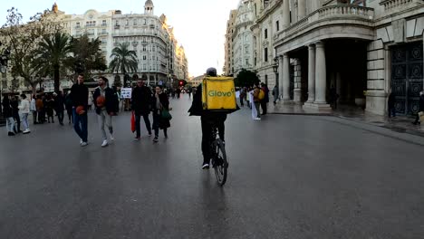 Glovo-cyclist-delivery-through-the-town-centre-in-Valencia,-Spain---Following-POV-shot