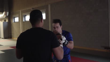 Two-amateur-boxers-having-a-training-session-in-the-indoor-gym-while-practicing-punches-on-the-gloves