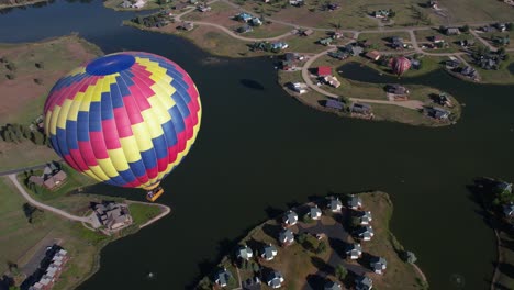 Hot-Air-Balloon-Parachute-Flying-Above-Lake-and-Houses,-Countryside-of-Colorado-USA