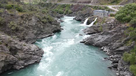 Ariel-footage-flying-up-the-Kawarau-river-passed-the-roaring-meg-power-station-in-Cromwell,-New-Zealand
