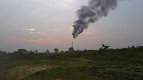 Plant-burning-oil-or-gas-with-strong-black-smokes-in-Bangladesh,-distance-view