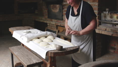 Georgian-Baker-Rolling-And-Shaping-Dough-On-Table-Then-Pressed-To-Stick-On-The-Wall-Of-Tone-Oven