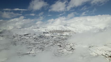 Drone-aerial-view-of-snow-covered-Mount-Hermon-and-Druze-town-Majdal-Shams,-Israel