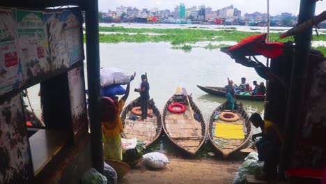 Passengers-with-sacks-on-their-heads-cross-the-Buriganga-river-via-a-boat-wharf-in-Dhaka,-Bangladesh