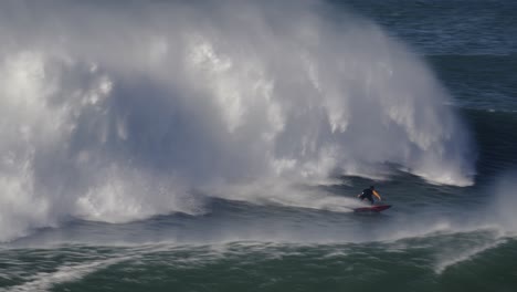Jet-ski-driver-riding-big-wave,-surfer-surfing-rough-ocean,-closeup-view,-real-speed,-Nazare,-Portugal