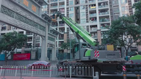 Workers-on-a-heavy-lift-crane-carry-out-repairs-of-huge-Chinese-city-village-entry-gate