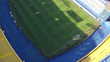 Aerial-top-down-shot-showing-team-of-Boca-Juniors-playing-soccer-in-stadium-during-sunny-day---Alberto-José-Armando-Stadium,Buenos-Aires