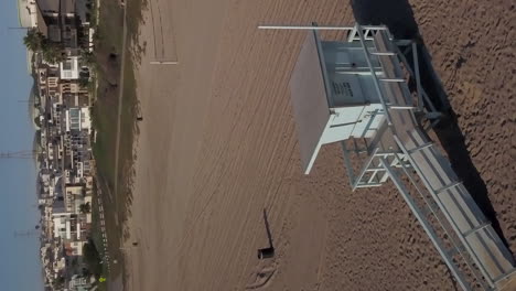 Lifeguard-tower-at-Manhattan-Beach-in-Los-Angeles,-California---aerial-vertical-orbit