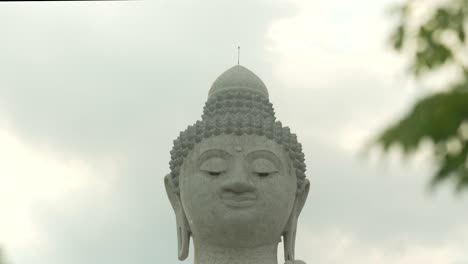 Der-Große-Buddha,-Phuket,-Thailand,-Zwischen-Palmblättern,-Geneigter-Schuss,-Bewölkter-Sonnenuntergang