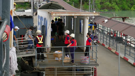 Tourist-and-local-depart-ferry,-workers-standby-in-safety-equipment