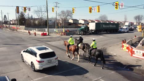 Mounted-Police-Unit-on-patrol-crossing-junction-Aerial-Tracking-Shot